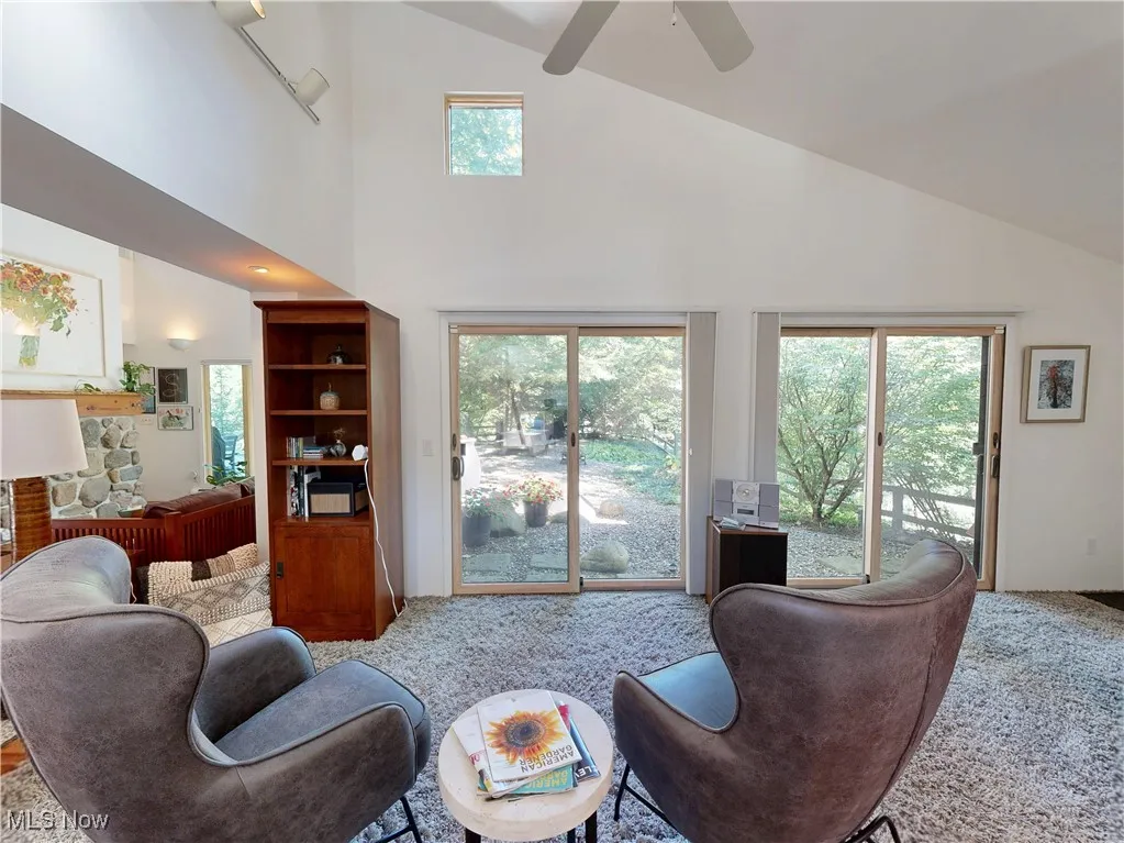 Living room with high vaulted ceiling, carpet, and ceiling fan