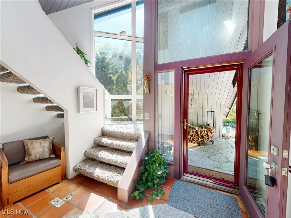 Tiled foyer featuring stairs and healthy amount of natural light