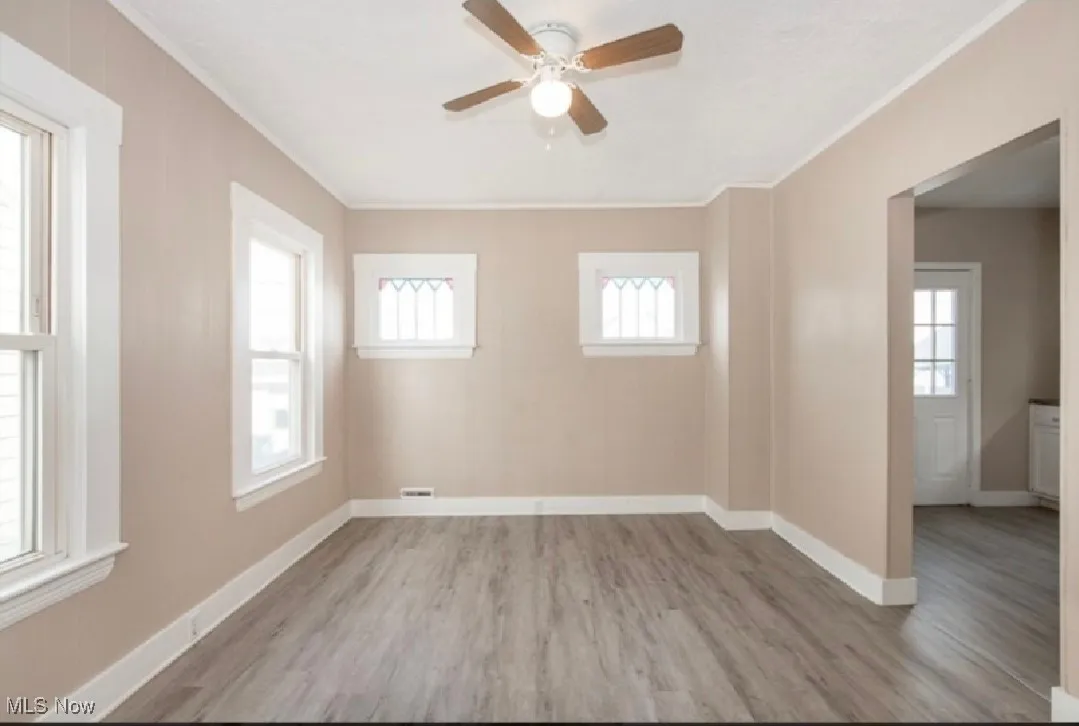 Empty room with light wood-type flooring, ornamental molding, and ceiling fan