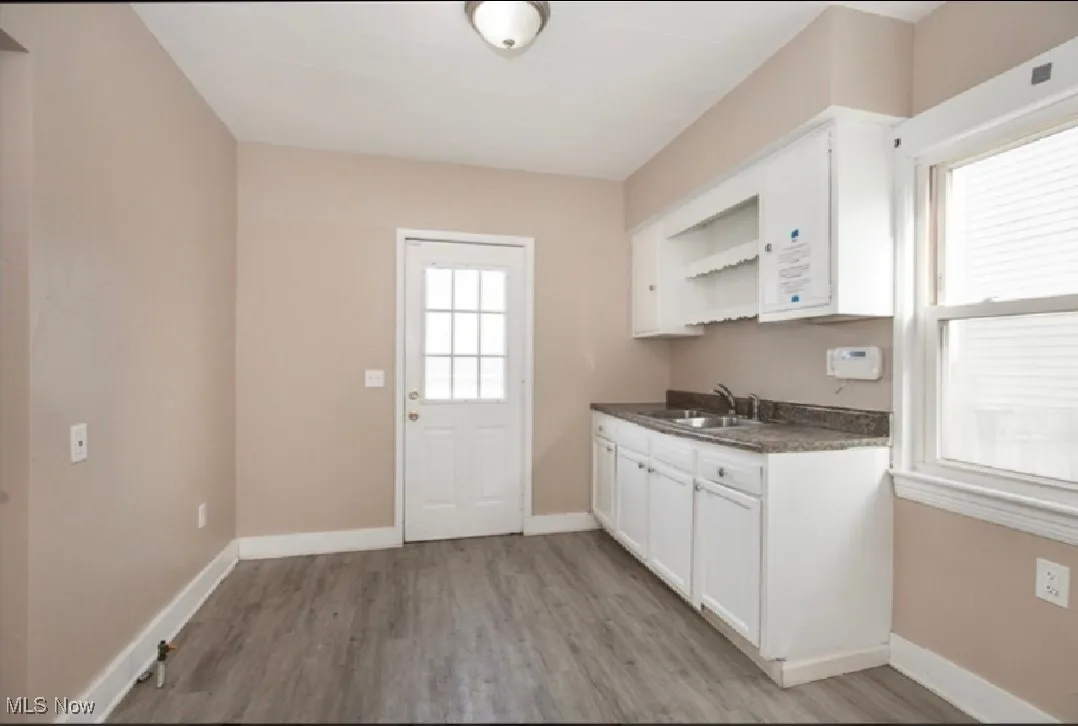 Kitchen featuring dark countertops, open shelves, white cabinetry, and light wood finished floors