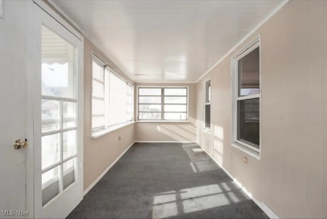 Unfurnished sunroom featuring carpet floors and baseboards