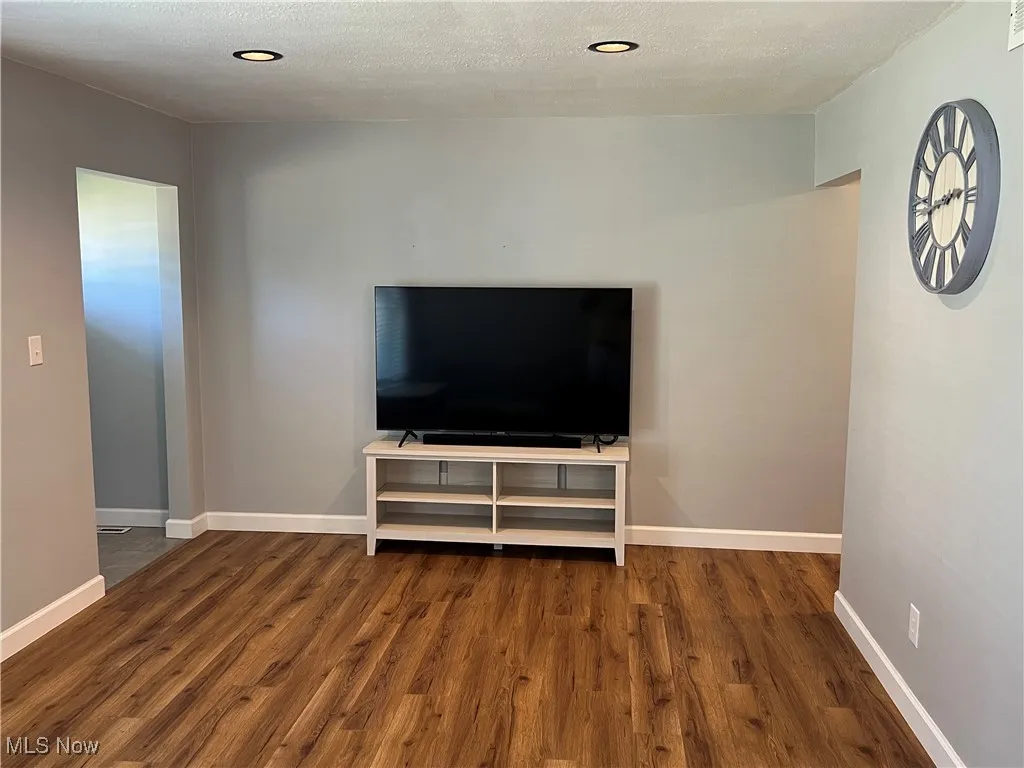 Unfurnished living room with a textured ceiling and dark wood-type flooring