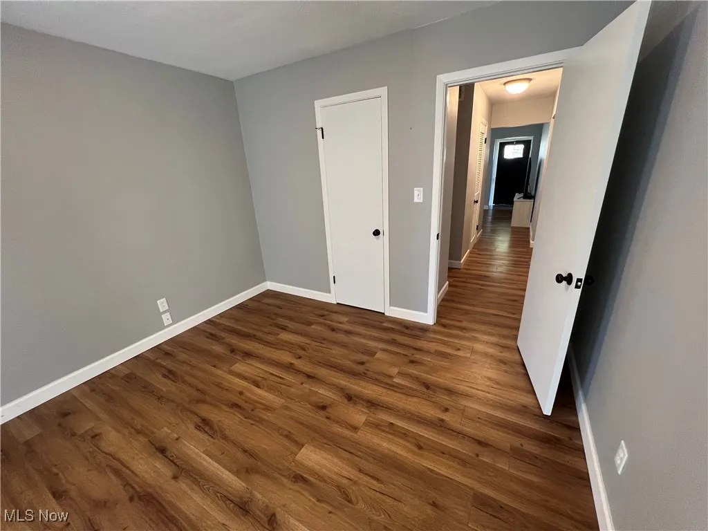Unfurnished bedroom with dark wood-type flooring
