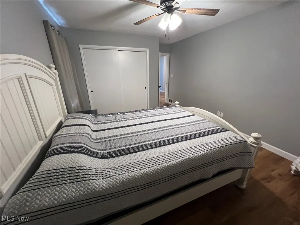 Bedroom featuring dark wood-style flooring, ceiling fan, and a closet