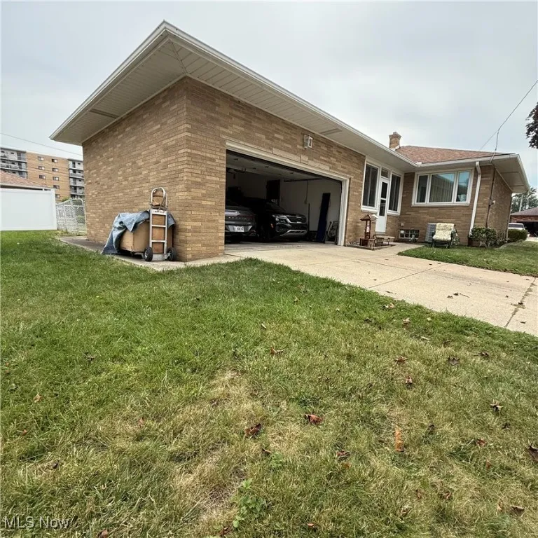 View of property exterior featuring brick siding, concrete driveway, and a yard