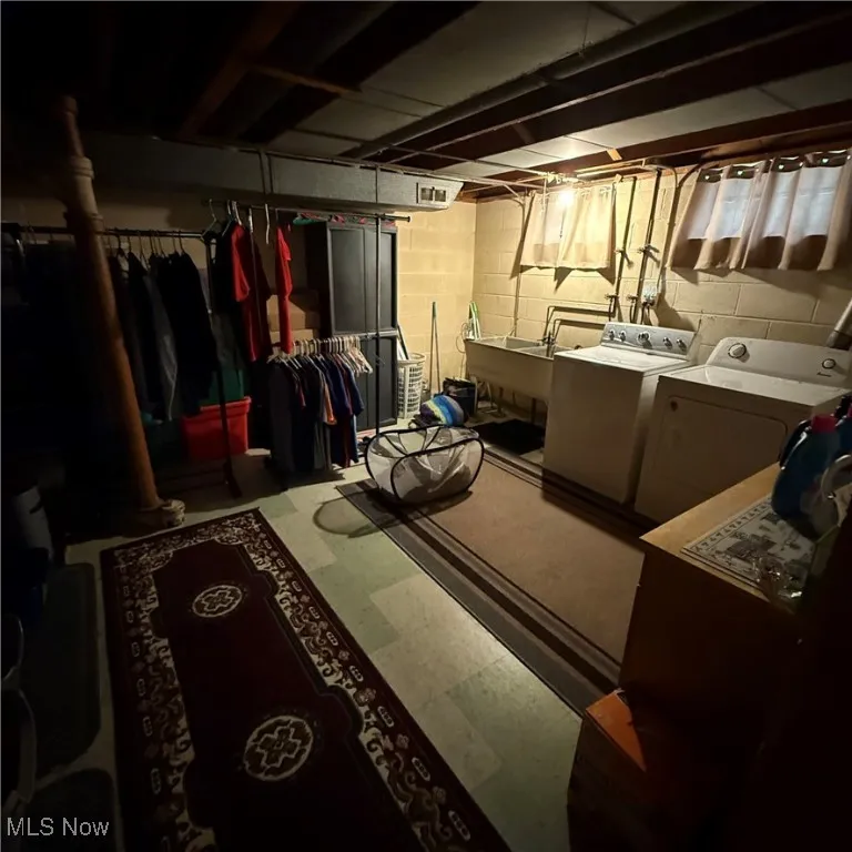 Unfinished below grade area with washing machine and clothes dryer and tile patterned floors