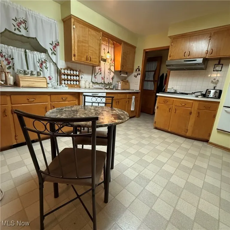 Kitchen with light flooring, light countertops, decorative backsplash, and brown cabinets