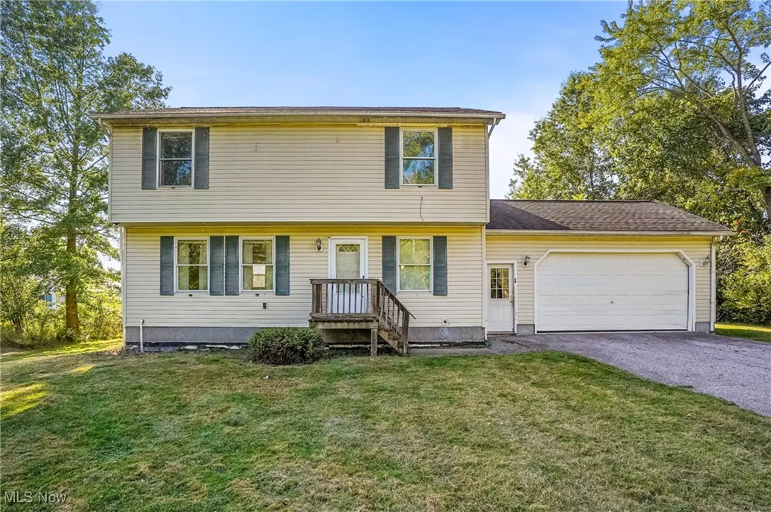 Colonial home featuring an attached garage, a front lawn, and driveway