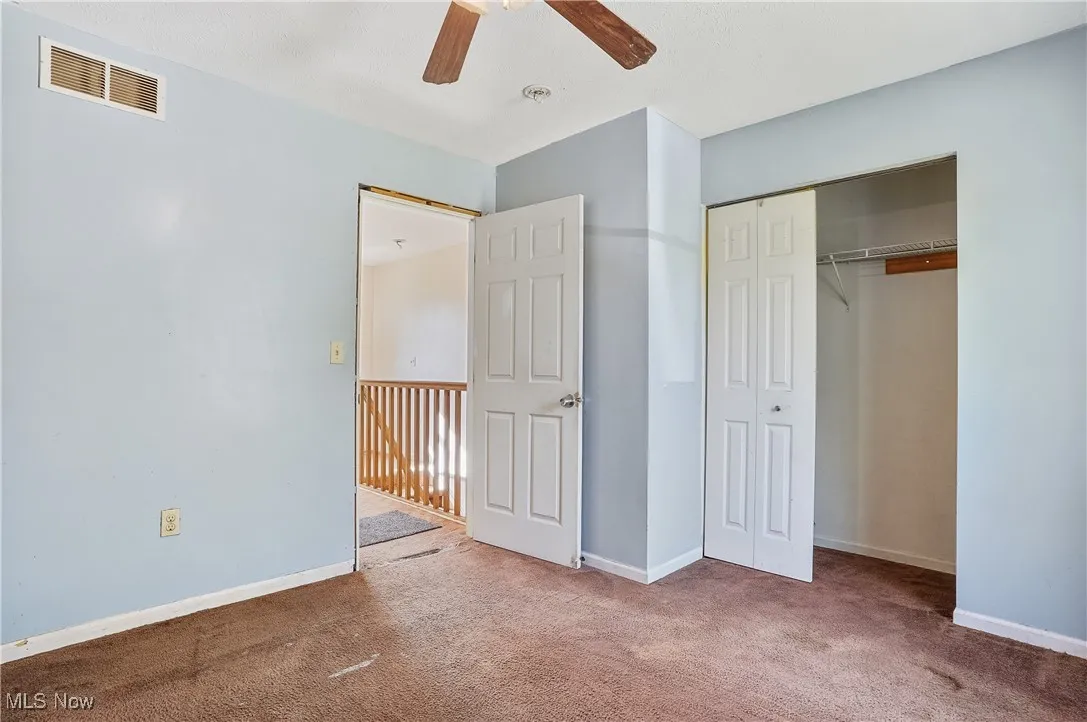 Unfurnished bedroom with carpet, a ceiling fan, and a closet