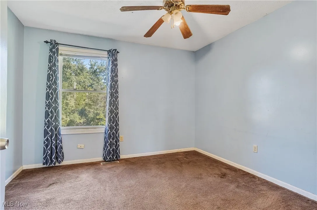 Empty room with carpet floors and a ceiling fan