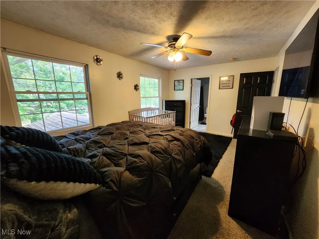 Carpeted bedroom featuring a textured ceiling and ceiling fan