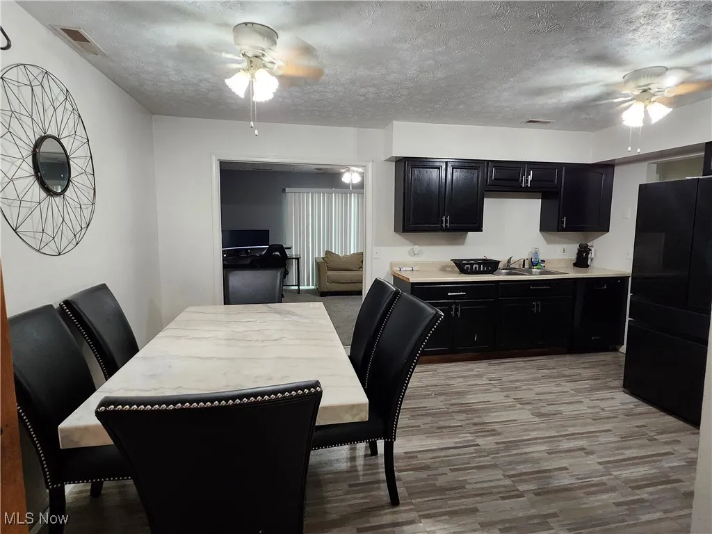 Dining area featuring a ceiling fan, a textured ceiling, and light wood-style floors