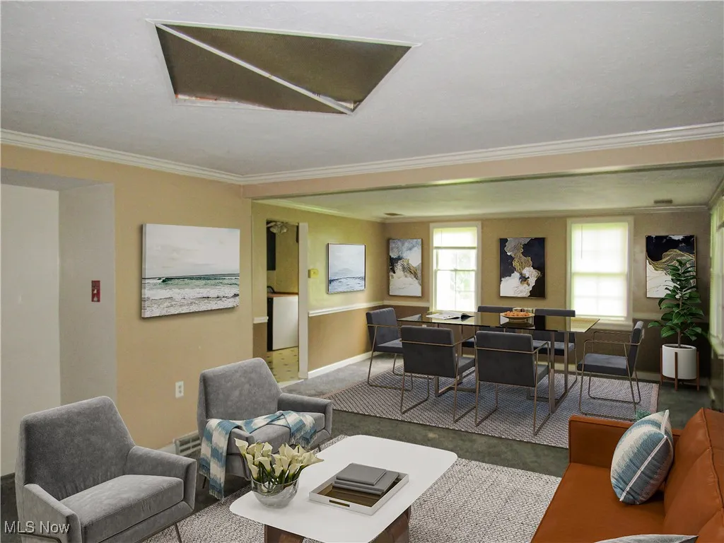 Carpeted living area featuring crown molding and baseboards