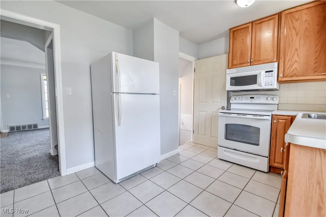 Another angle of the kitchen showing refrigerator and side entrance