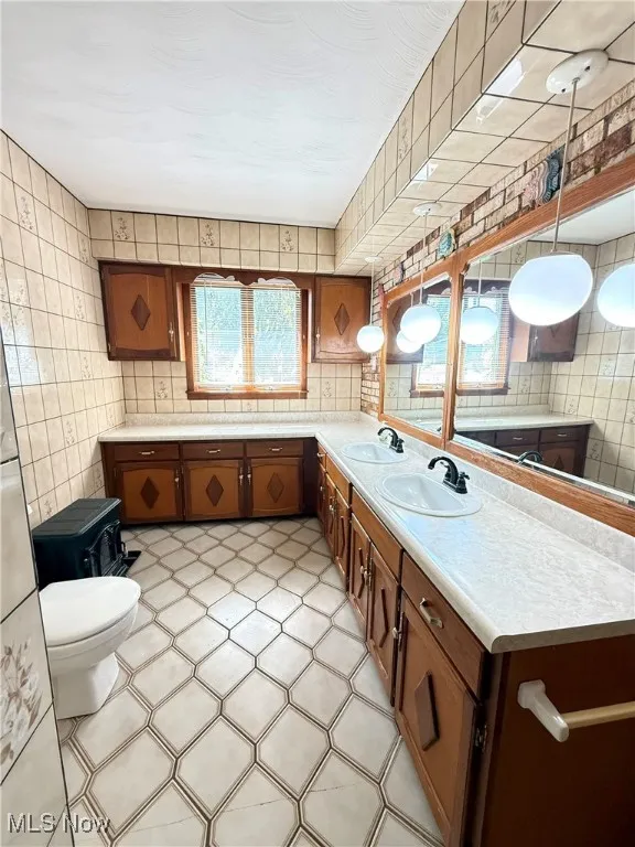 Kitchen with light countertops, tile walls, brown cabinetry, and light tile patterned floors