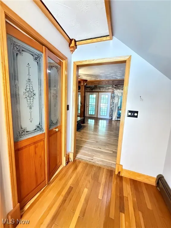 Hall with light wood finished floors and baseboard heating