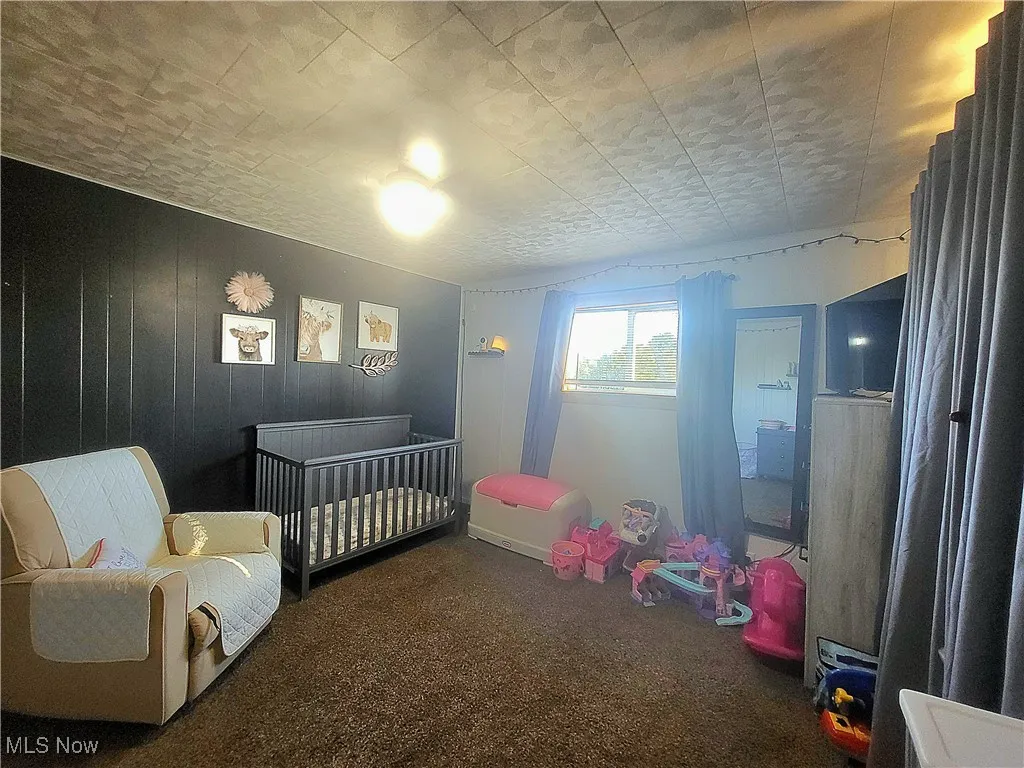 Bedroom featuring carpet flooring and a crib
