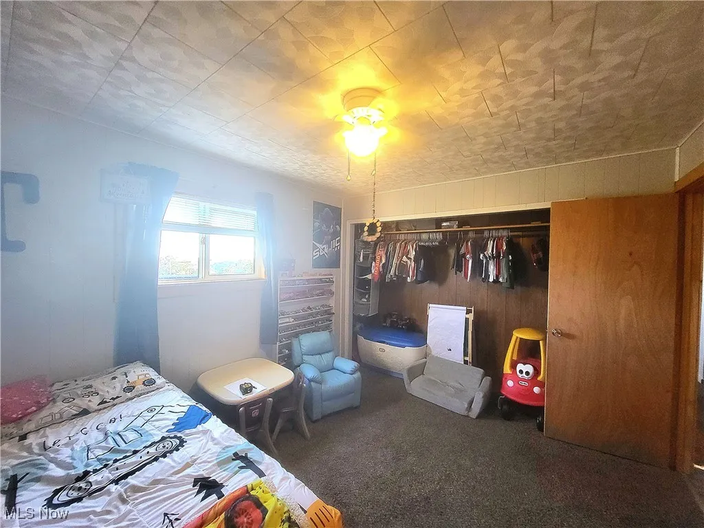 Carpeted bedroom with a closet and wooden walls