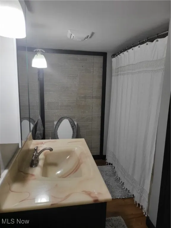Full bath with vanity, dark wood-style floors, and curtained shower