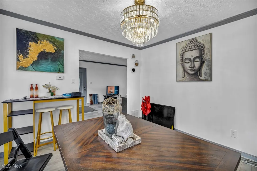 Dining area with a textured ceiling, crown molding, and a chandelier