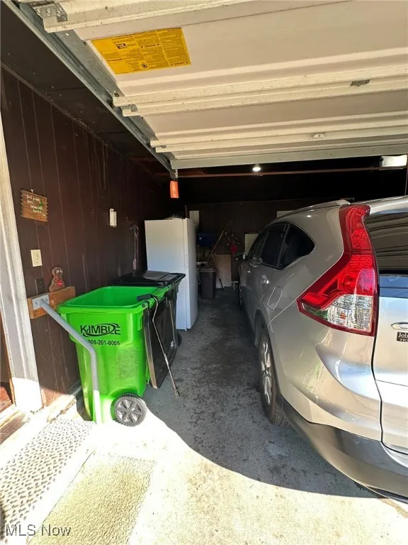 Garage featuring freestanding refrigerator and wood walls