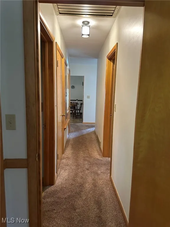 Corridor featuring carpet floors and baseboards