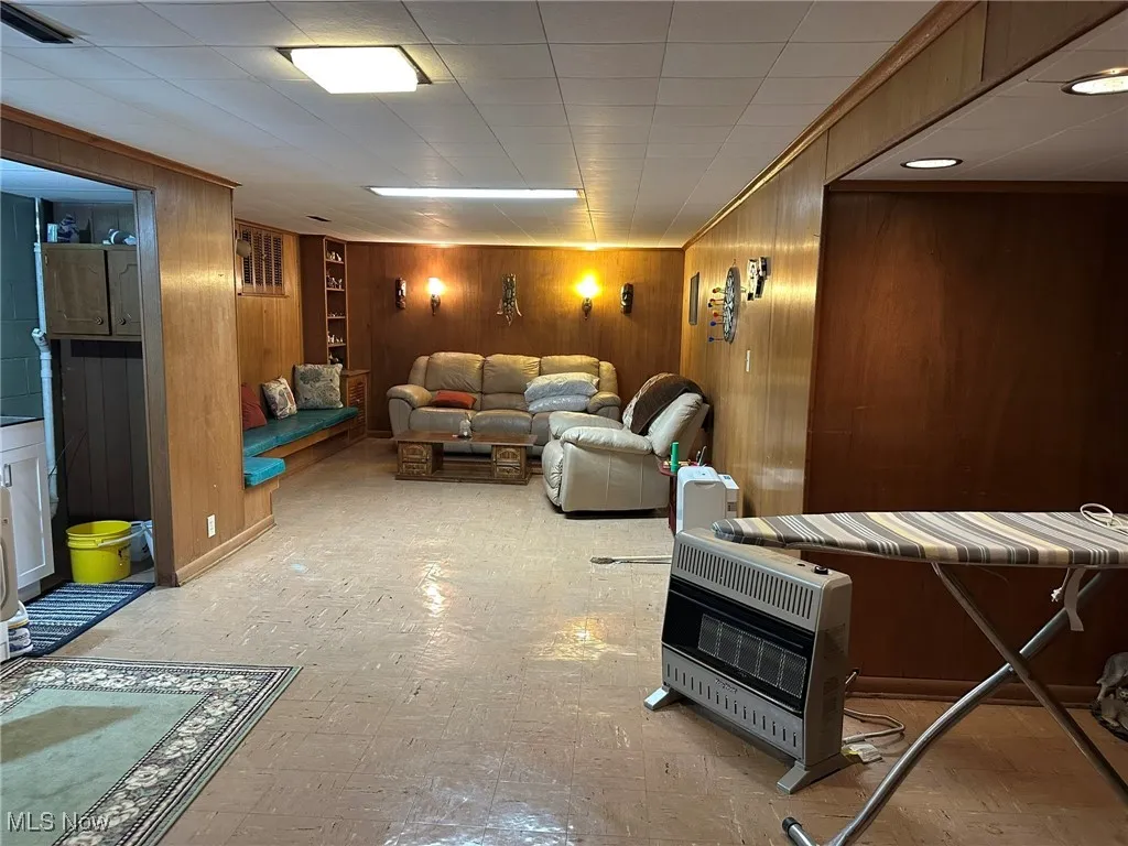 Home theater featuring wood walls, heating unit, and light floors