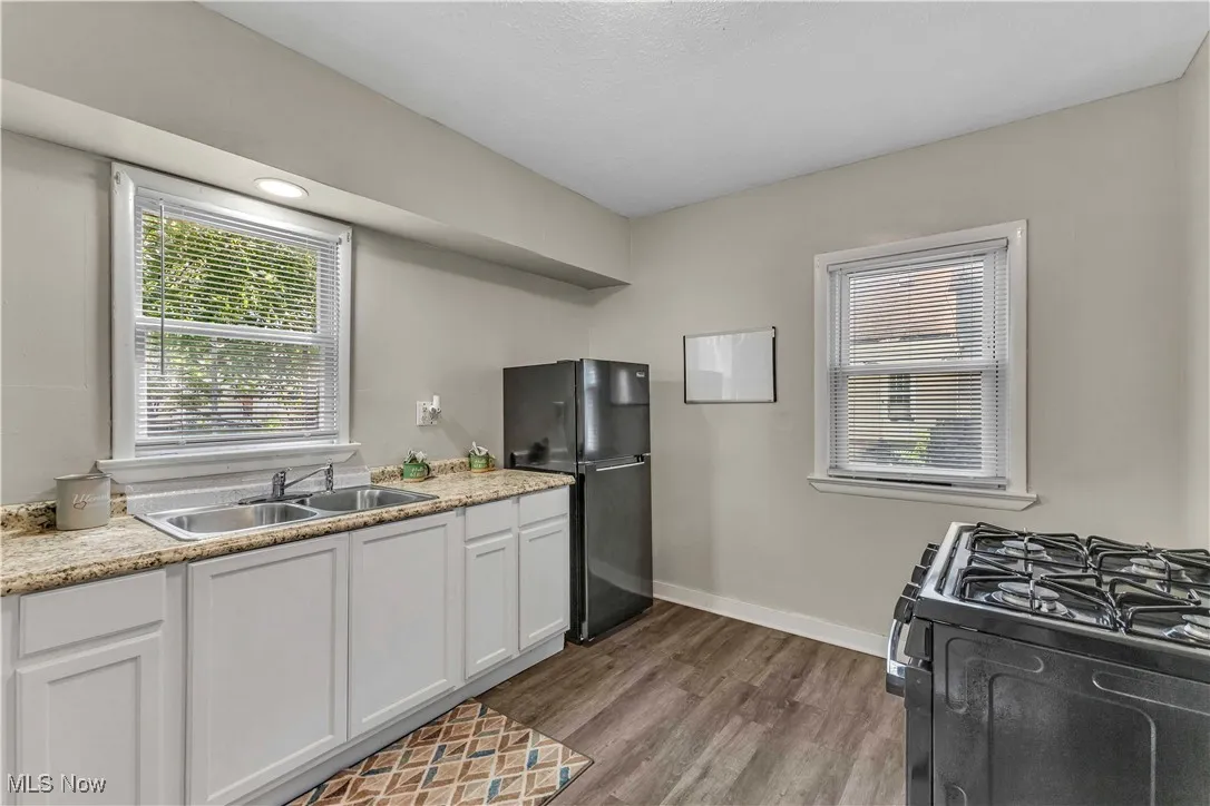 Kitchen with black appliances, white cabinets, and dark wood finished floors