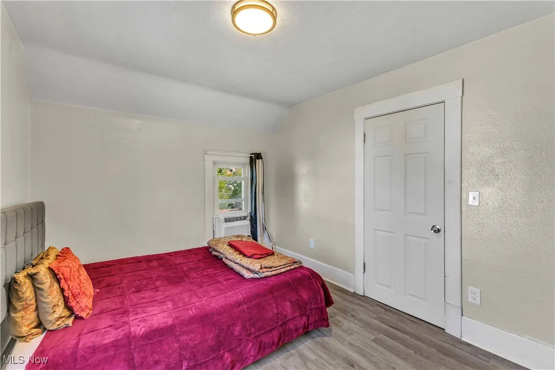 Bedroom with wood finished floors, vaulted ceiling, and a textured wall