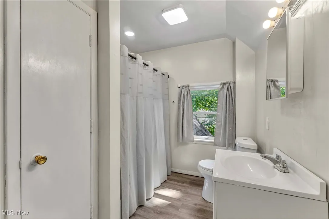 Full bathroom featuring vanity, light wood-type flooring, lofted ceiling, and a shower with shower curtain