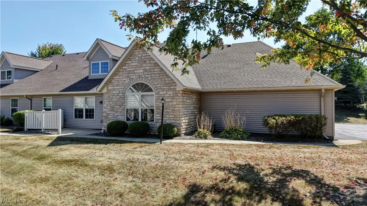 Cape cod home featuring a shingled roof, stone siding, and a front lawn