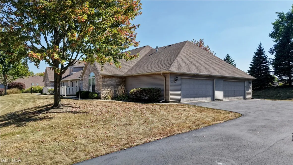 View of front of property featuring an attached garage, a shingled roof, a front yard, and asphalt driveway