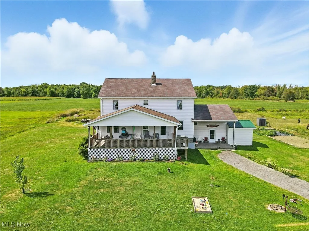 Front view of property featuring a view of countryside, a chimney, a lawn, a wooden deck, and roof with shingles