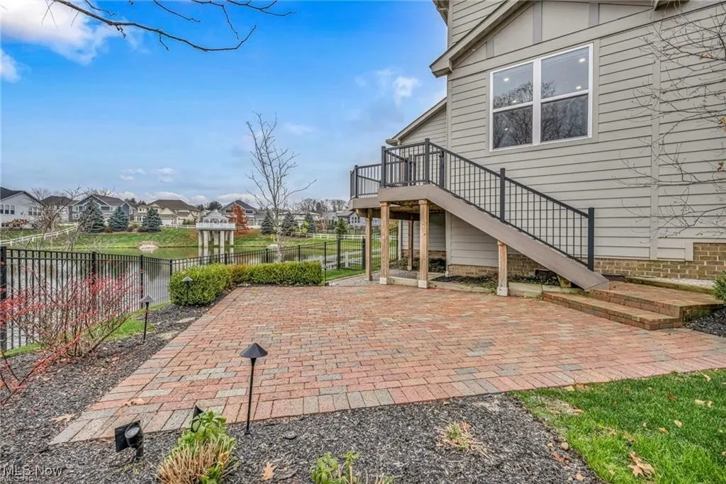 View of patio with stairway, a deck with water view, and a residential view