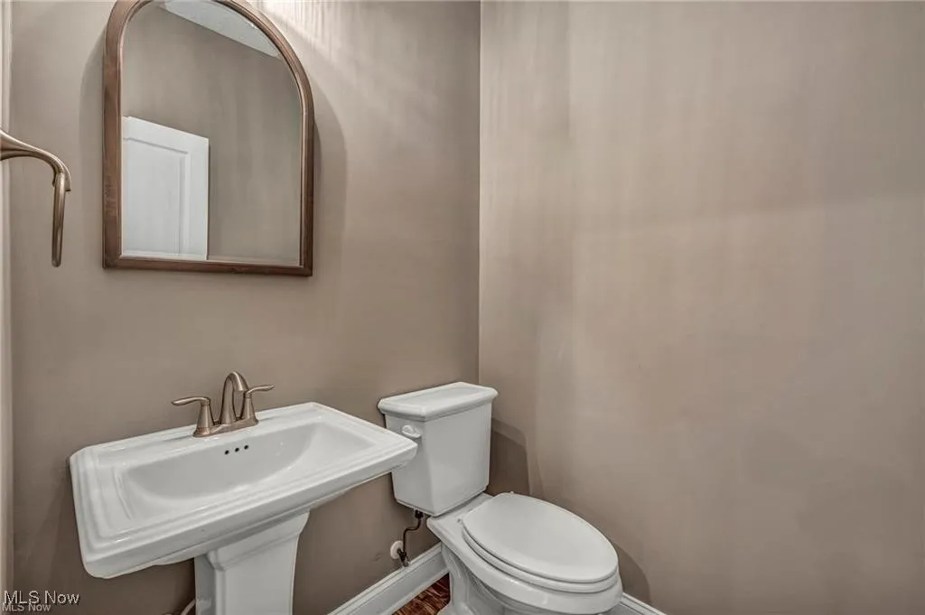 Half bath with baseboards and toilet