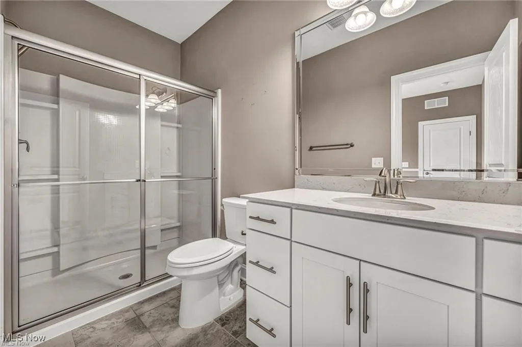 Full bath with vanity, a shower stall, and dark tile patterned flooring