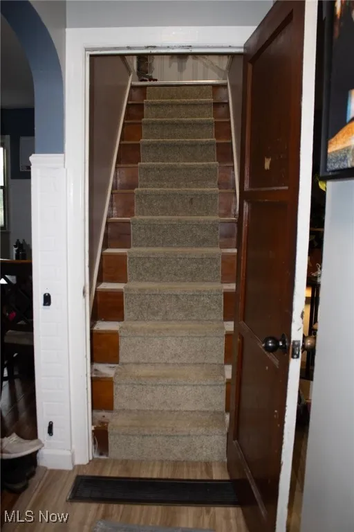 Stairway with wood finished floors and arched walkways