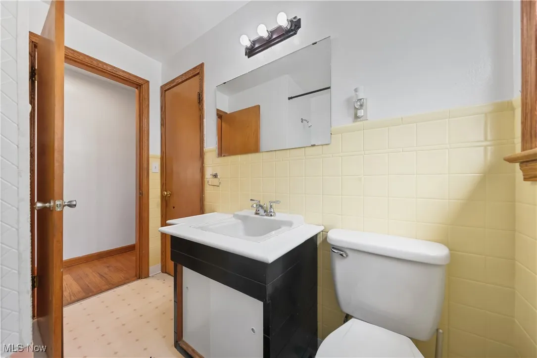Half bath featuring vanity, light flooring, and tile walls