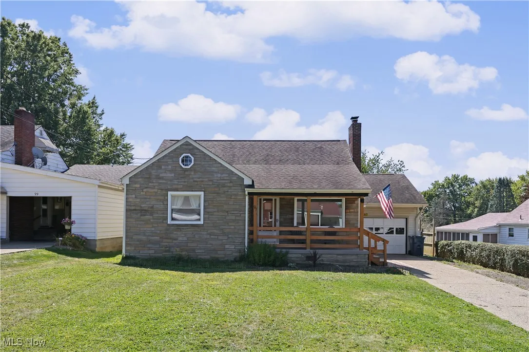 View of front of property with covered porch, a front yard, a chimney, and driveway