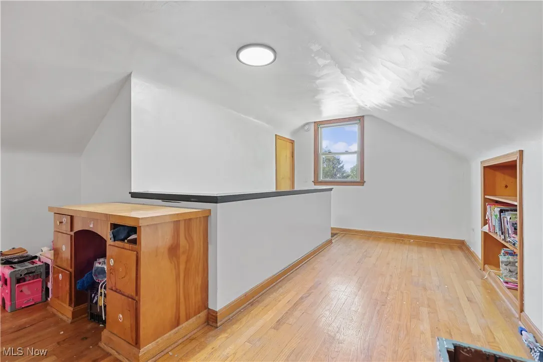 Bonus room with lofted ceiling and light wood-type flooring