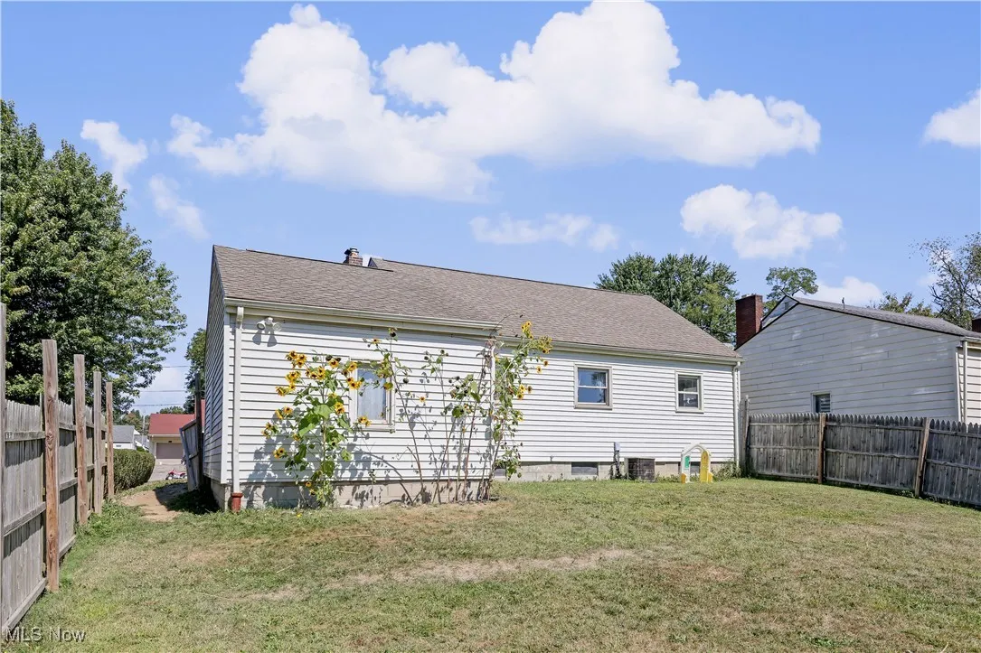Back of property with a fenced backyard, roof with shingles, and a chimney