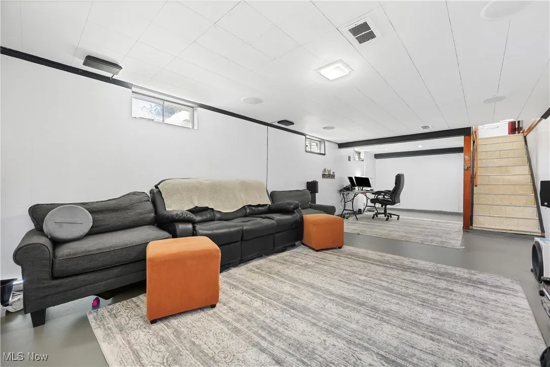 Living room with concrete floors, stairs, and a desk