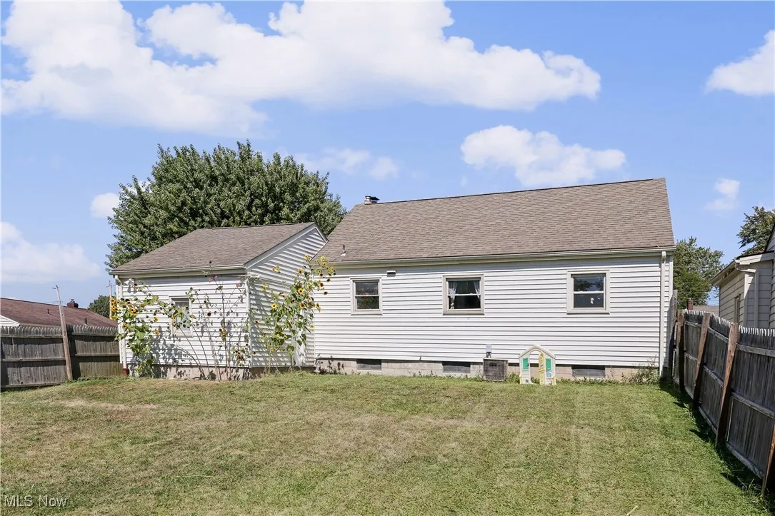 Back of property with a fenced backyard and a shingled roof