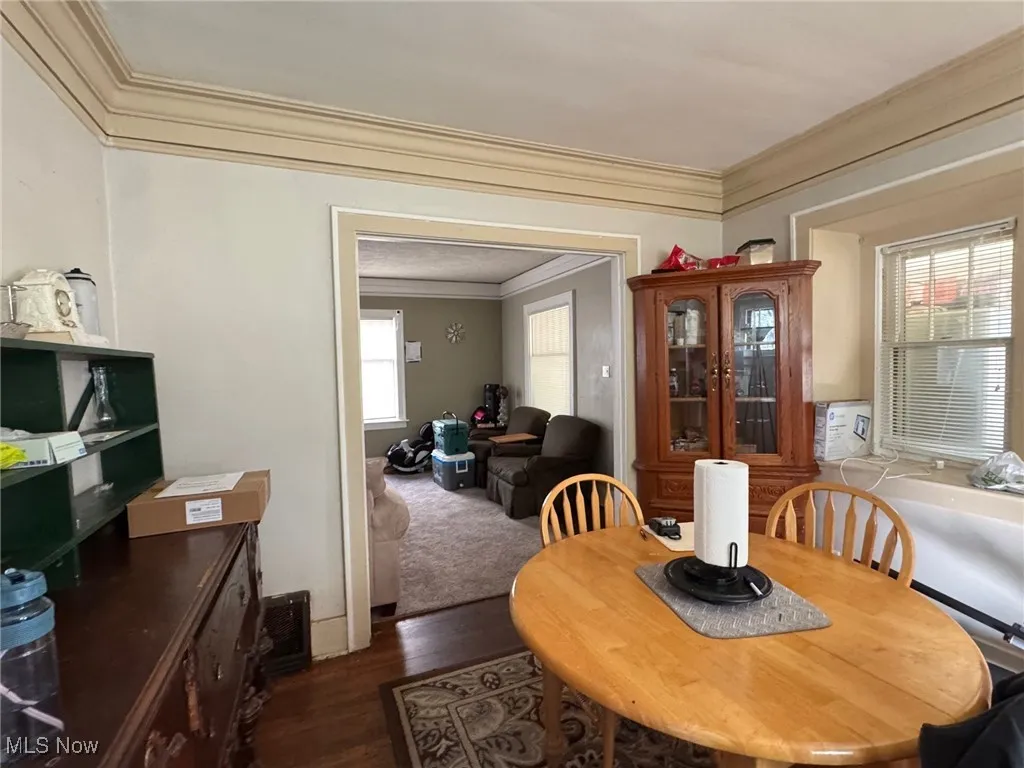 Dining room with ornamental molding and dark wood-style flooring
