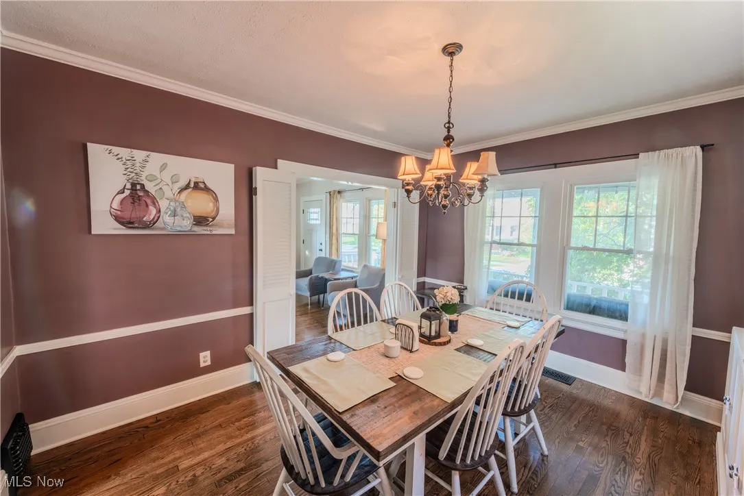 Bright dining room featuring a chandelier, ornamental molding, hardwood floors.
