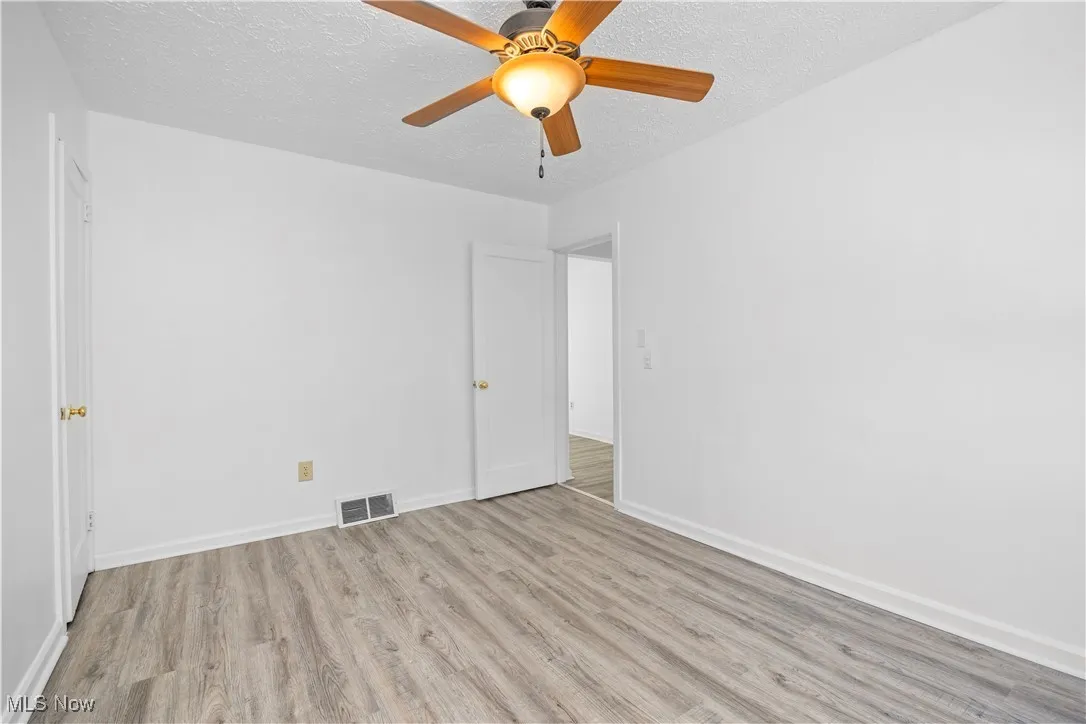 Unfurnished bedroom with light wood-style flooring, ceiling fan, and a textured ceiling