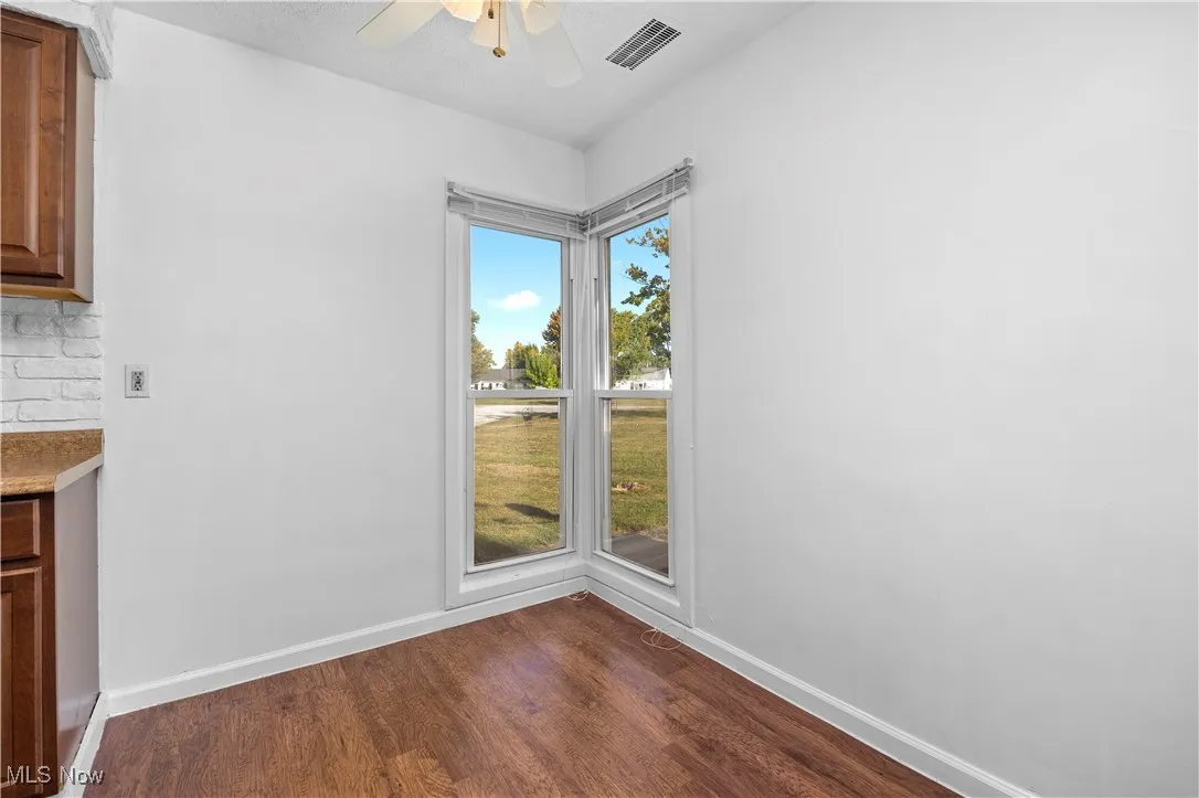 Unfurnished dining area featuring dark wood-style floors and ceiling fan