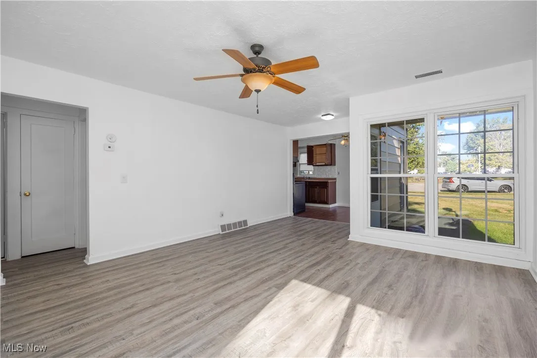 Unfurnished living room featuring light wood-style flooring, ceiling fan, and a textured ceiling