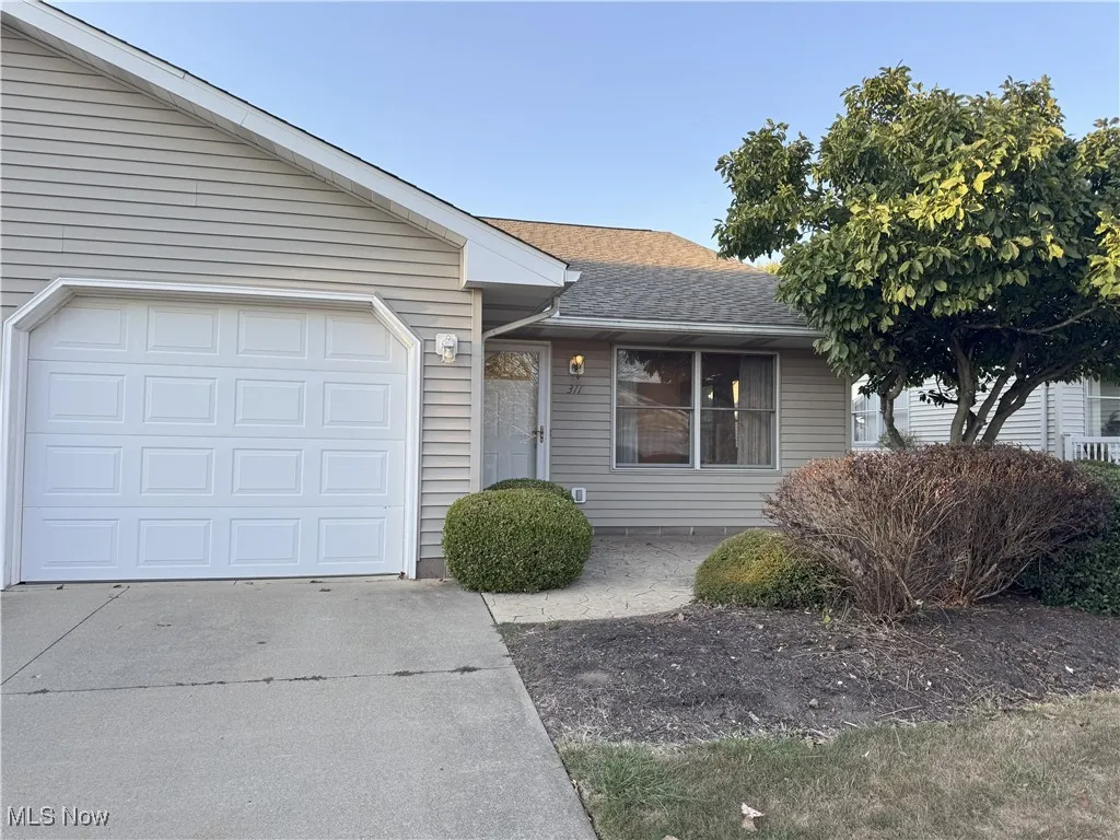Ranch-style home with roof with shingles, concrete driveway, and an attached garage