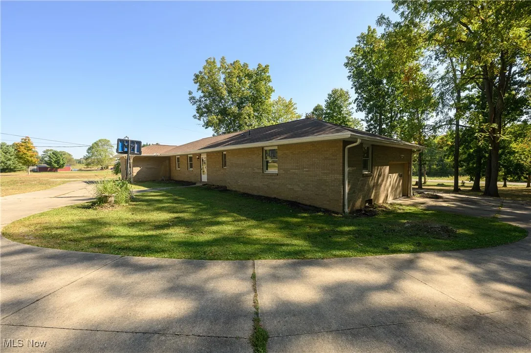 View of side of property featuring brick siding, a lawn, and driveway